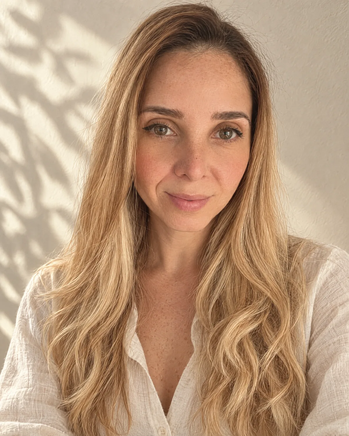 Retrato de Erika sonriendo, con luz natural y camisa de lino clara